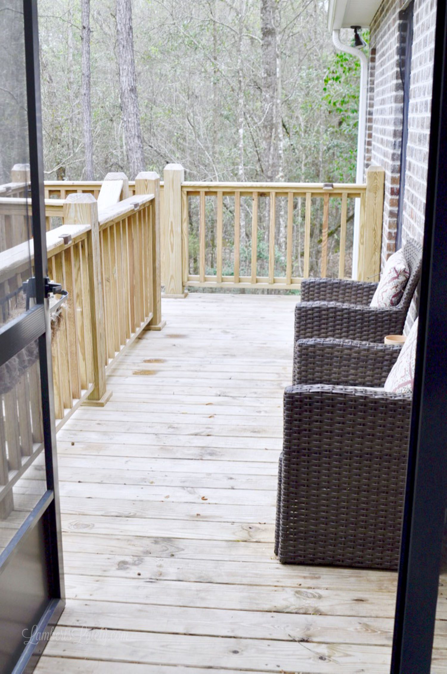 wood deck on back of house with two brown wicker chairs.