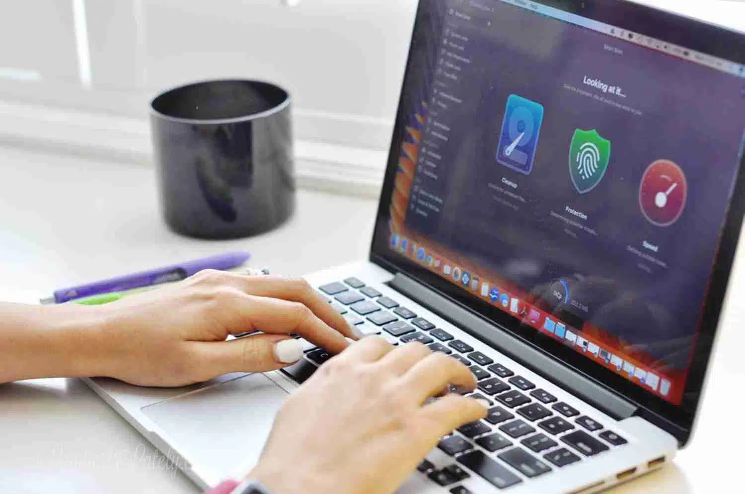 typing on a macbook pro on a desk, with cleanmymac open.