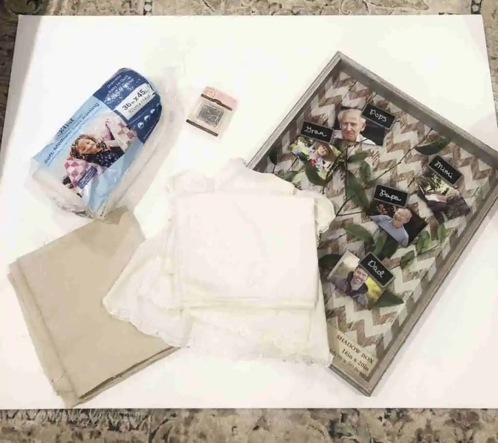 supplies for a framed baby outfit laid out on a floor.