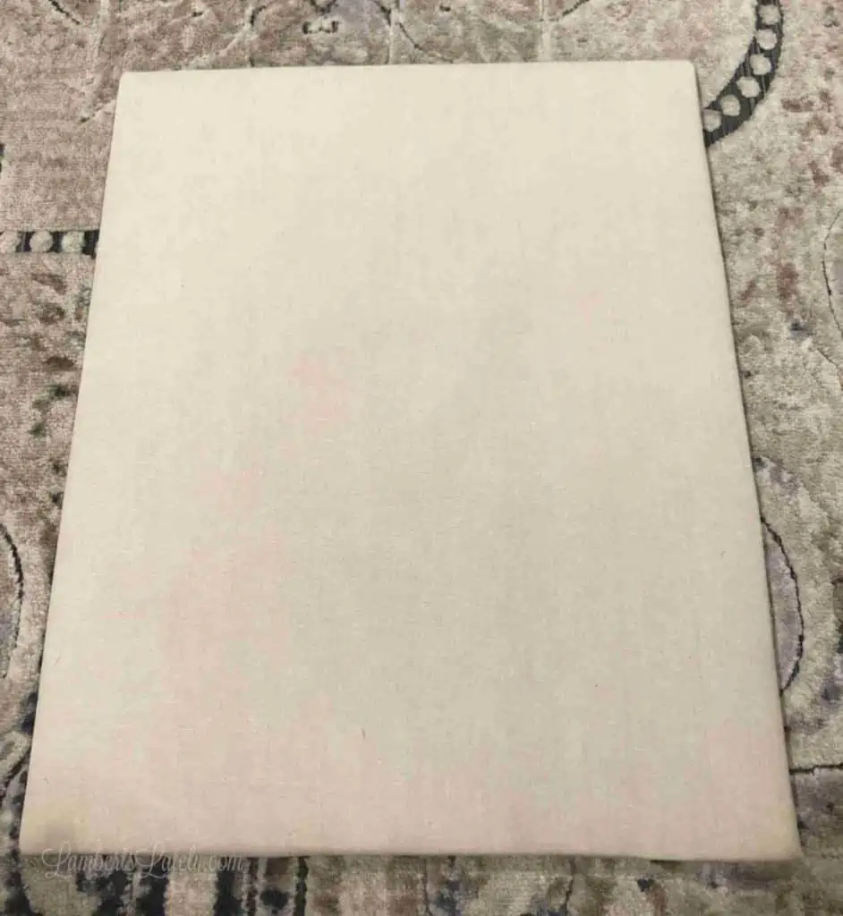 brown cloth wrapping the back piece of a shadow box.