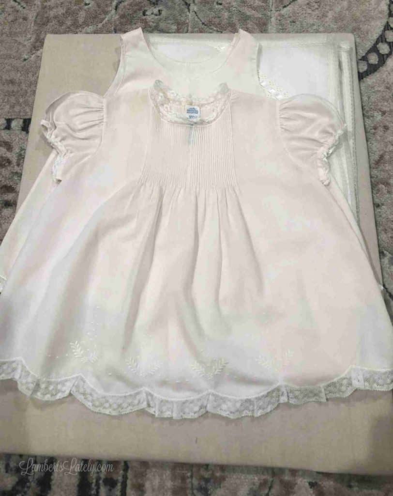 baby dress laid on a piece of brown cloth to be framed.