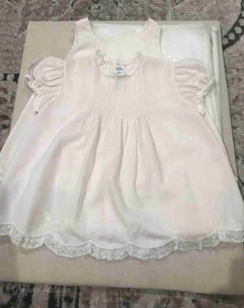 baby dress laid on a piece of brown cloth to be framed.