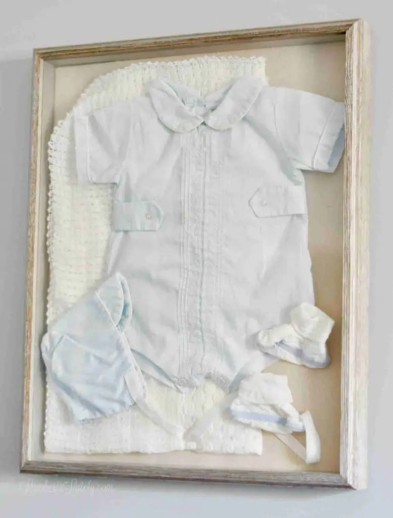 blue baby outfit framed in a shadow box.