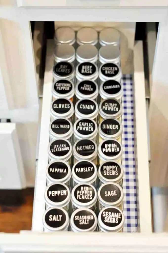 open spice cabinet with black glass spice jars lined in rows.