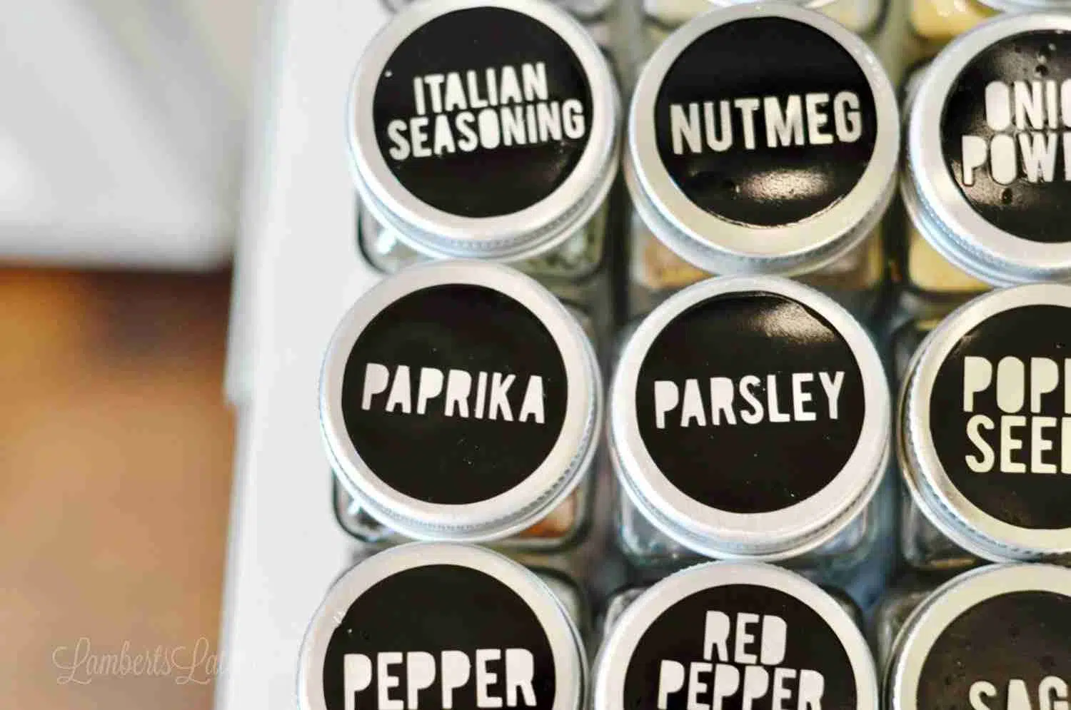 spice jars with black labels lined in a spice cabinet.