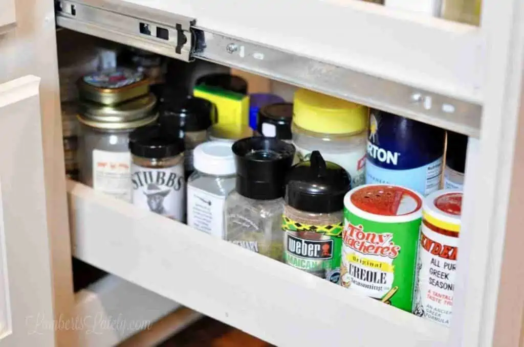 extra mismatched spices in bottom shelf of a spice cabinet.