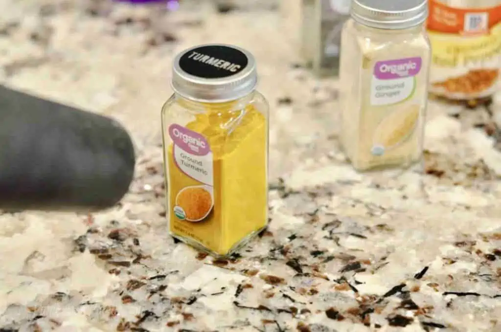 yellow turmeric in a glass spice jar with a black label on top.