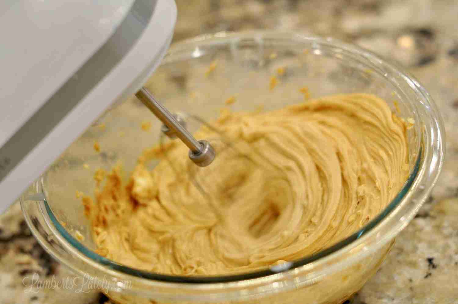 mixing peanut butter frosting with a hand mixer.