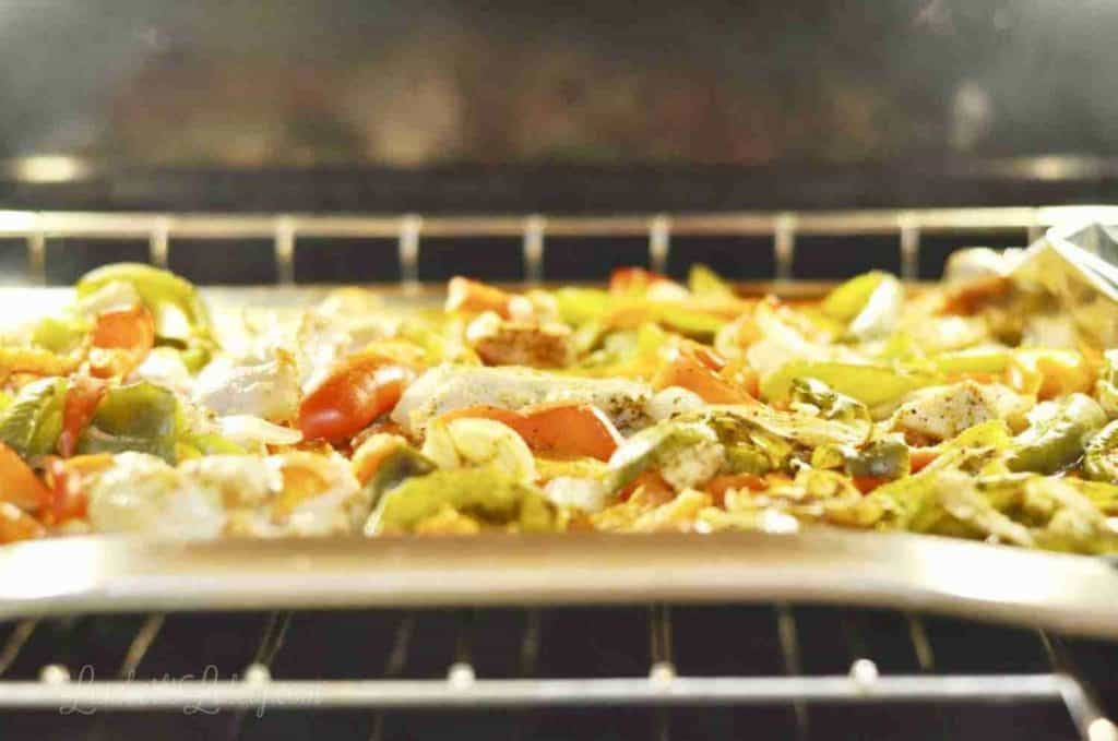 chicken fajitas on a sheet pan in an oven.