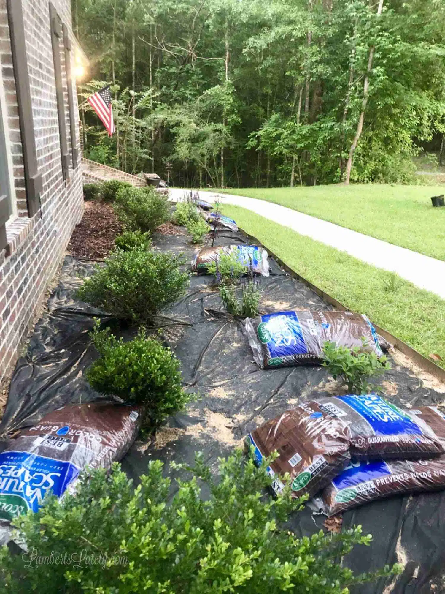 flower bed before adding mulch, with mulch bags surrounding bed.