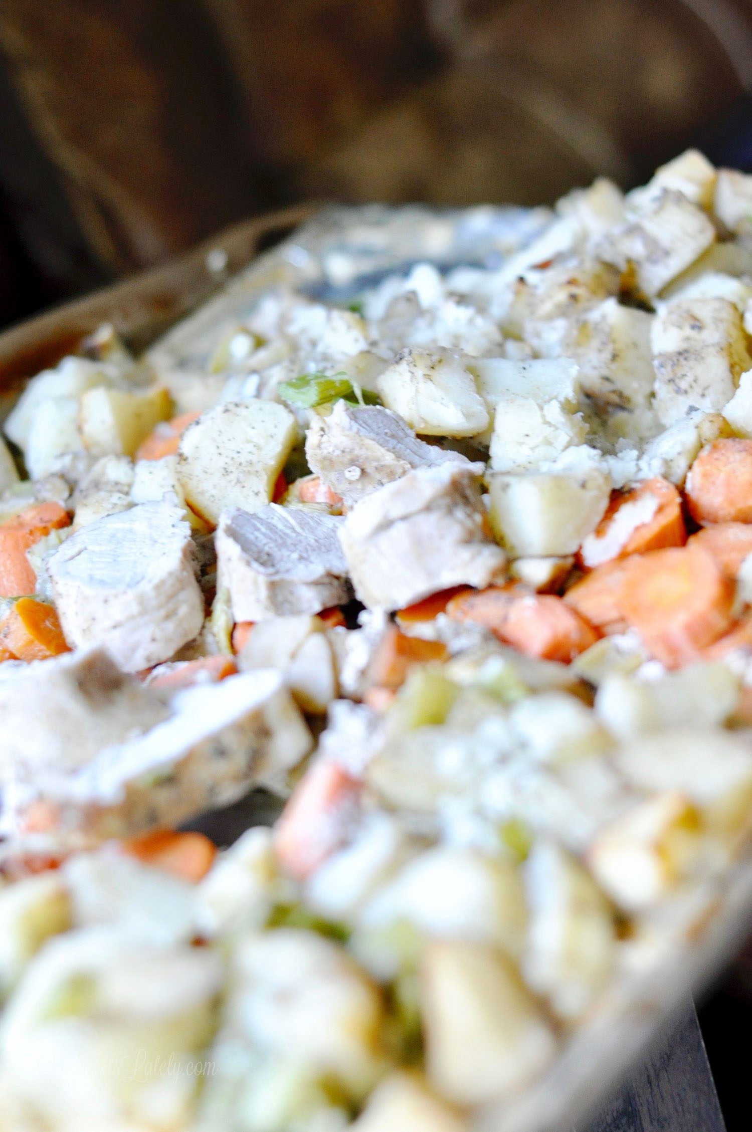 pork tenderloin, carrots, potatoes, apples, and celery on a sheet pan.