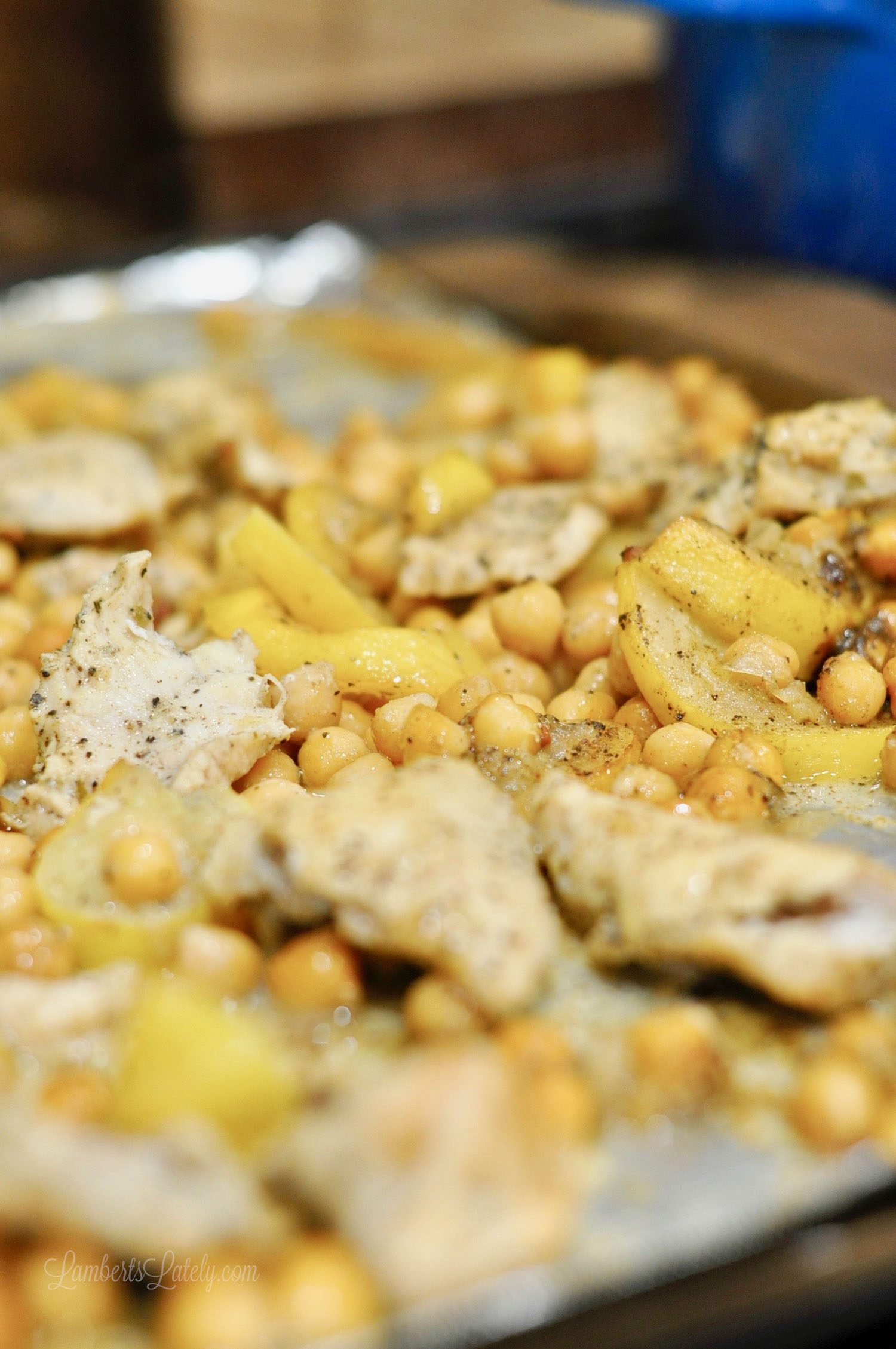 chicken, lemon, and chickpeas on a sheet pan covered in foil.