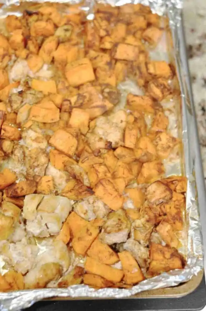 chicken and sweet potatoes on a sheet pan lined with foil.