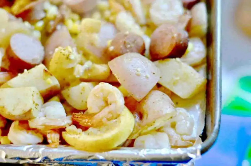 shrimp, potatoes, sausage, and lemon slices on a sheet pan.