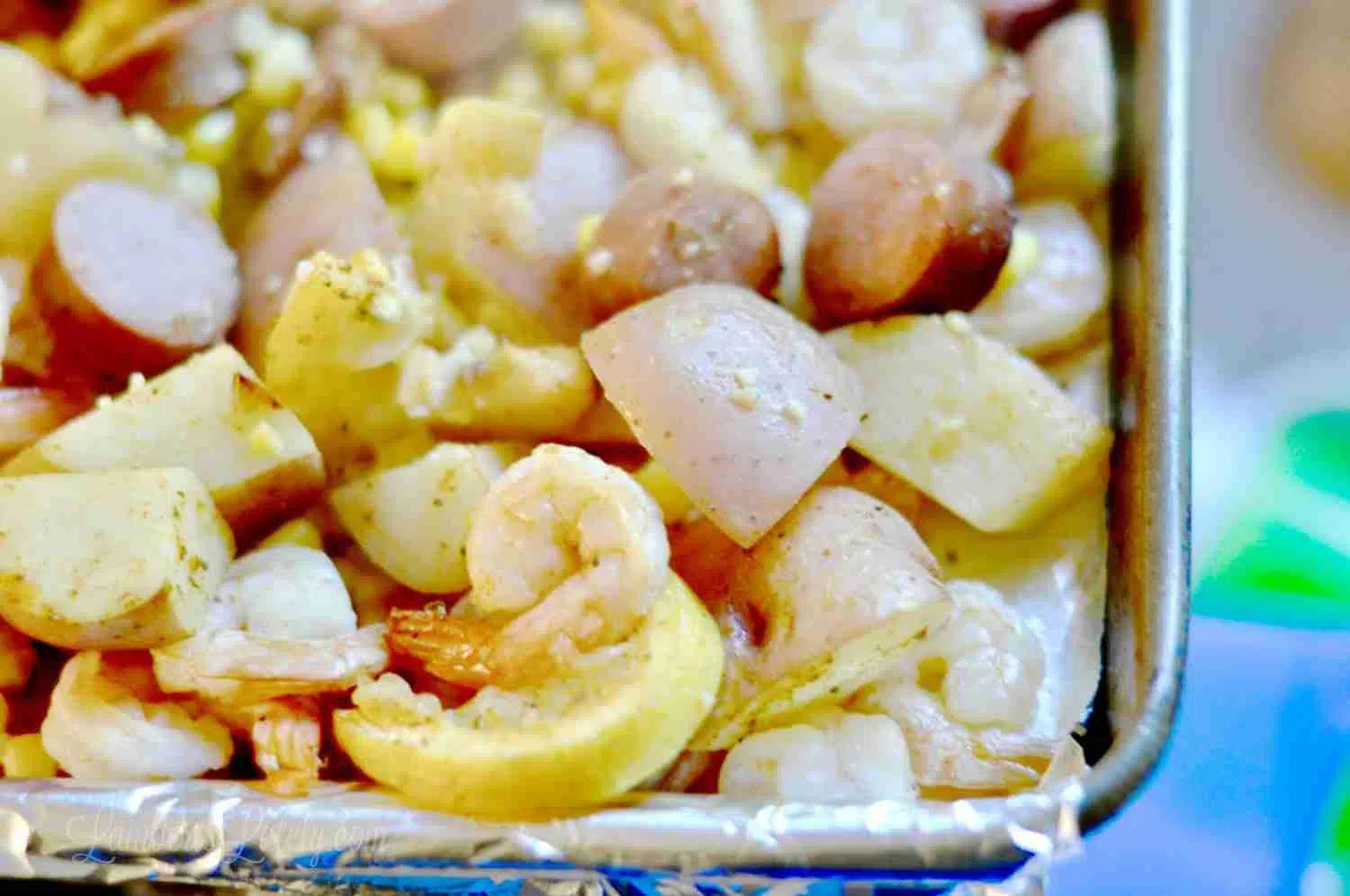 corner of a sheet pan with shrimp, potatoes, and lemon.