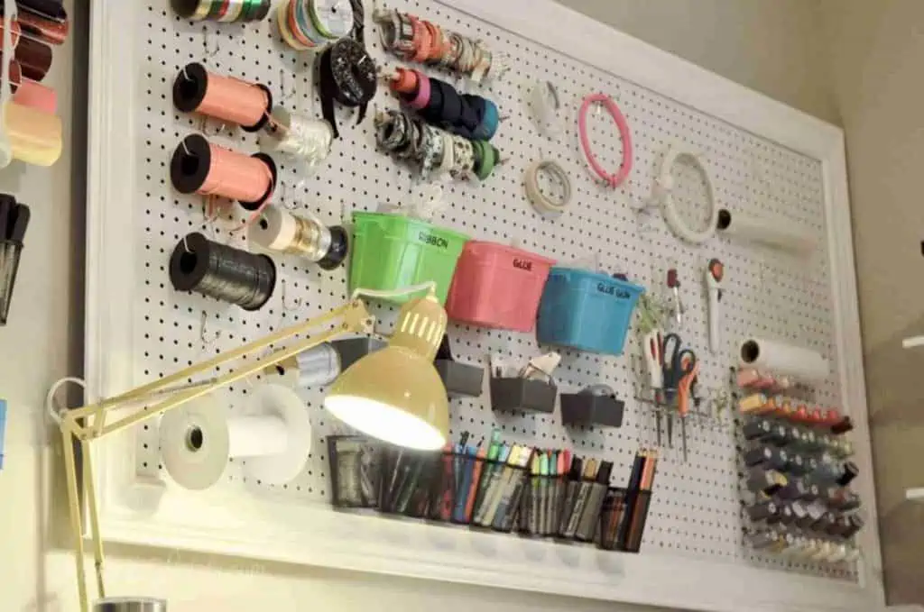craft room peg board with yellow desk light.