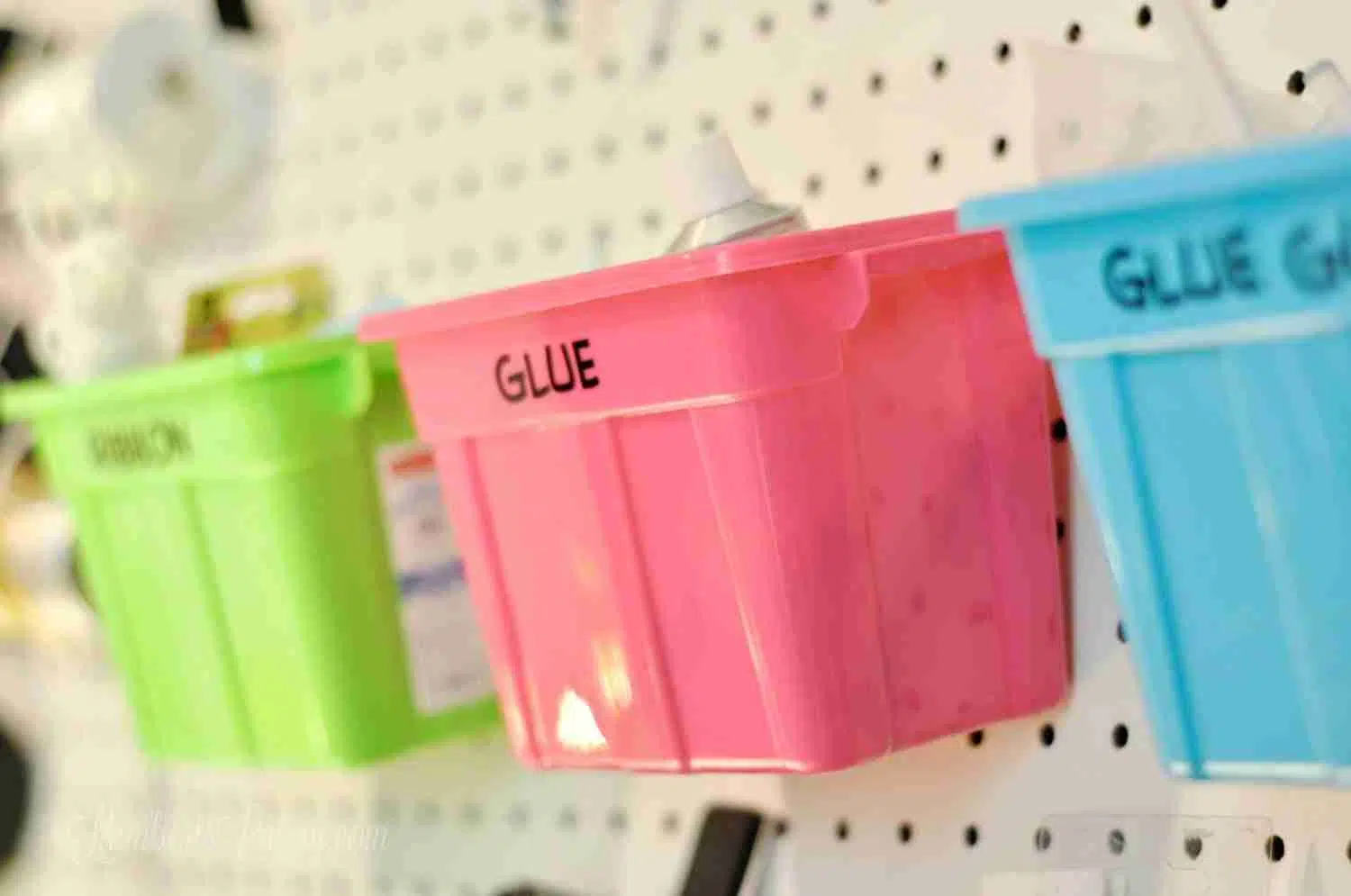 green, pink, and blue plastic bins hung on a peg board.