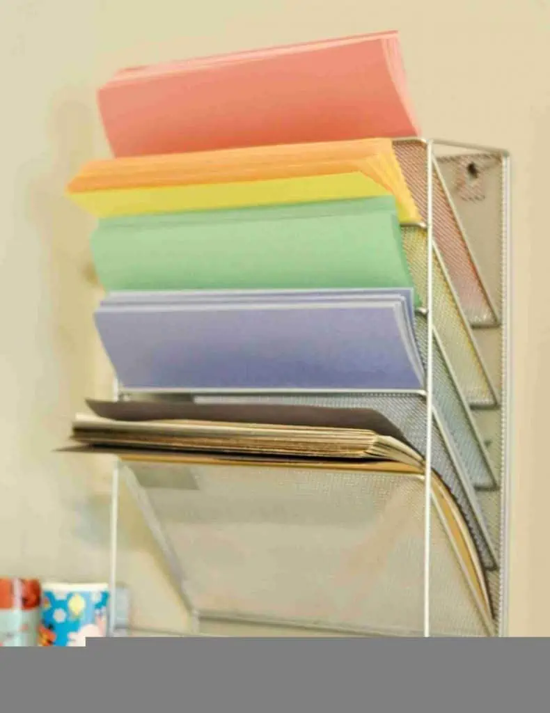 colorful construction paper organized in a metal rack on a wall.