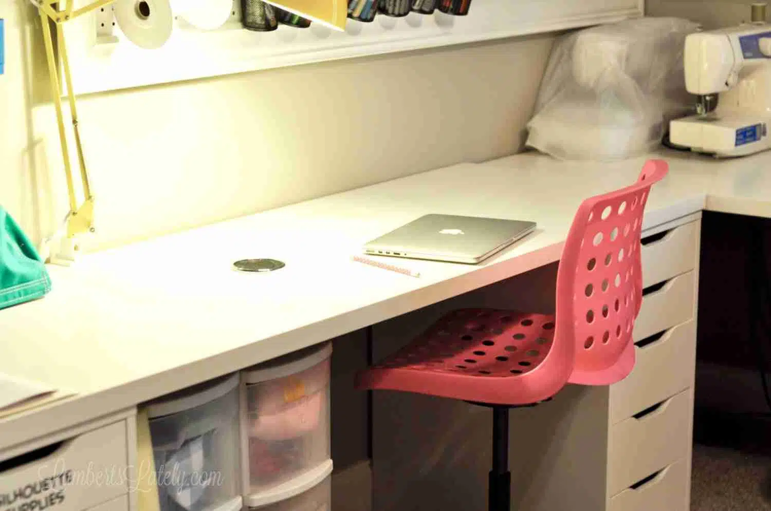 pink office chair at a white desk, with desk light on.