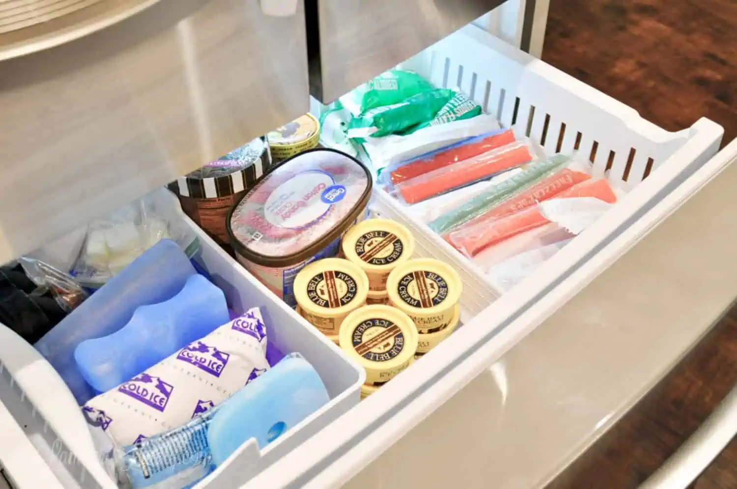 top of a drawer freezer filled with food and organized into sections
