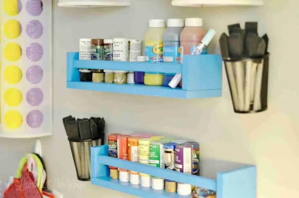 blue wooden shelves hanging on a wall, holding paint jars