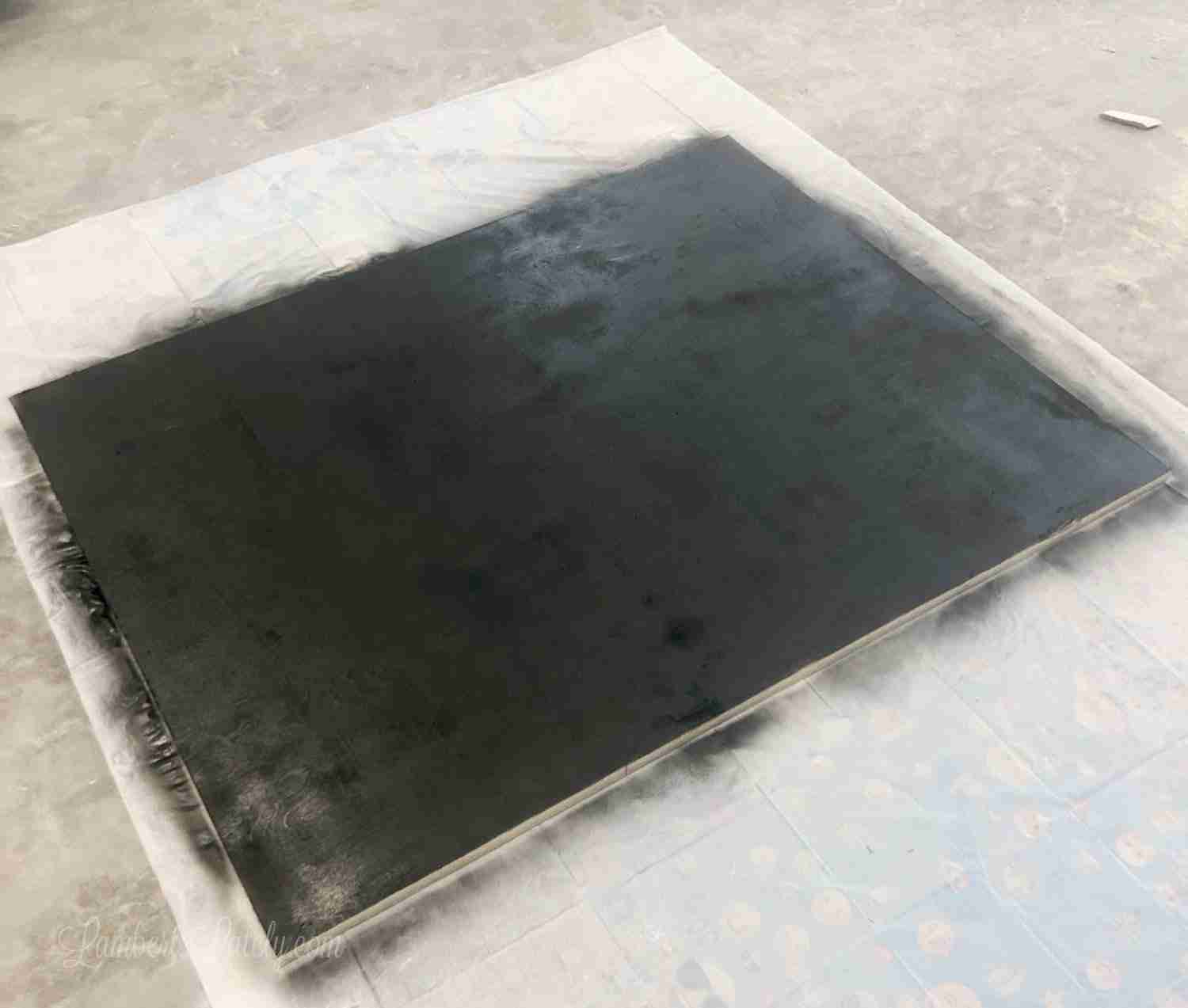 spray painting a desk bottom with chalkboard paint.