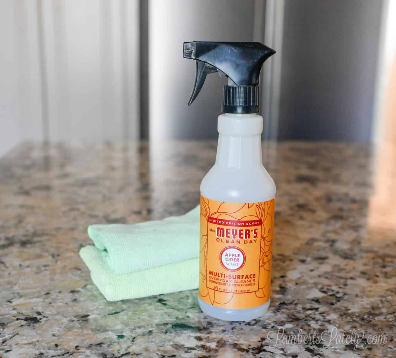 bottle of mrs meyers and microfiber cloths on a granite countertop.