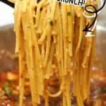 Spicy chicken pasta with chili onion crunch, garnished with herbs, close-up shot.