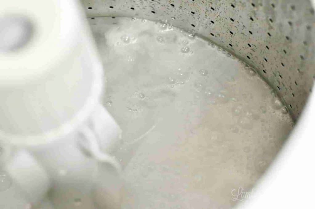 drum of washing machine filled with water, vinegar, and baking soda.