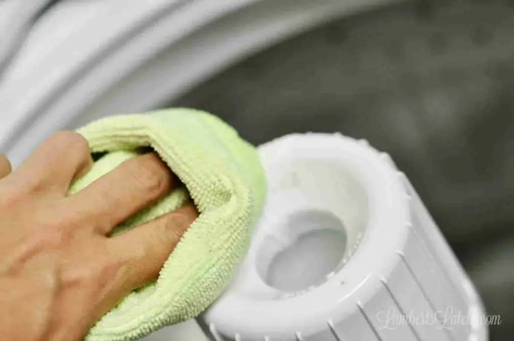 using a microfiber cloth to clean a fabric softener dispenser in a top load washing machine.