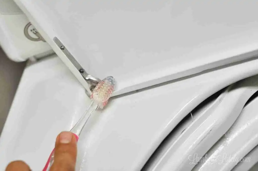 cleaning brackets of a washing machine door with a toothbrush.