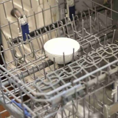 bowl of vinegar in the middle of the dishwasher rack.