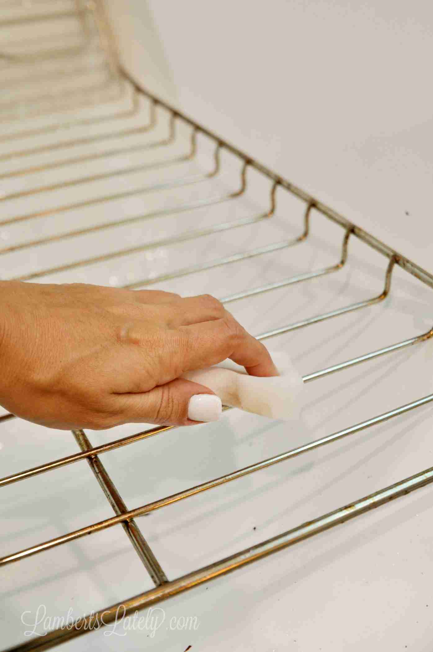 scrubbing an oven rack with a melamine sponge