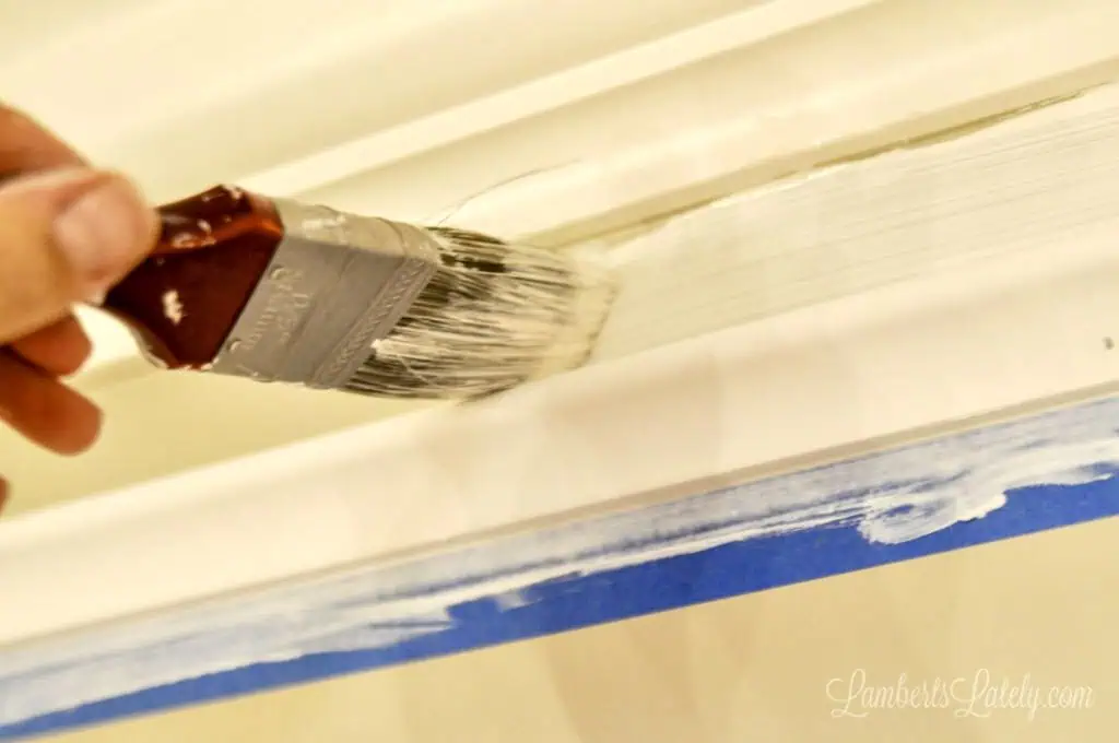 brushing paint onto gap between two pieces of molding.