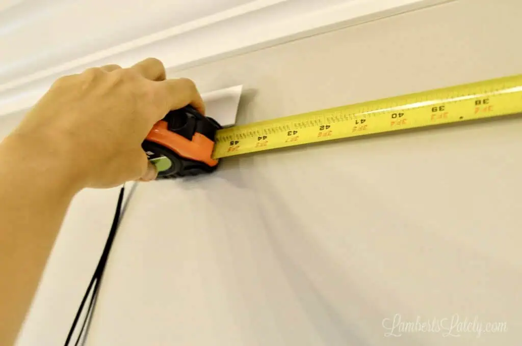 measuring molding on a wall with a tape measure.