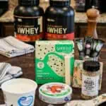 Assorted macro-friendly snacks including protein powder, yogurt, and snacks on a table.