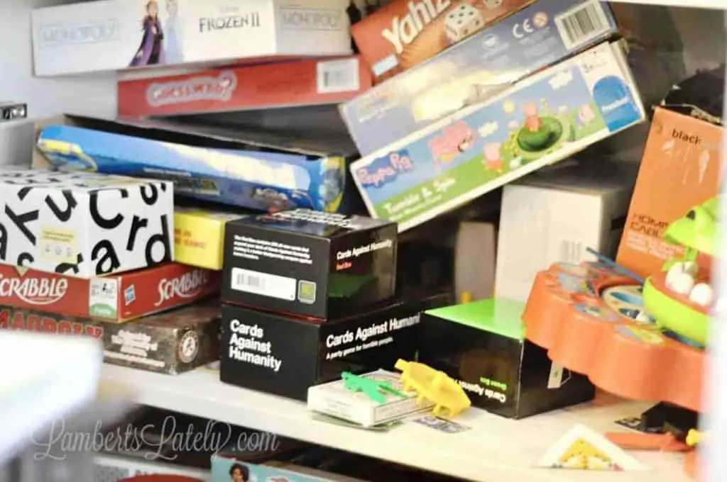 board game storage cabinet before organizing, full of cardboard boxes