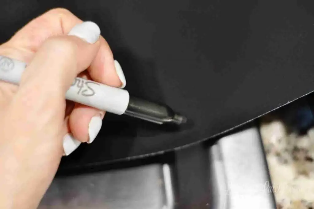 tracing the shape of a stove on the splatter guard with a sharpie