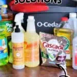 Collection of mopping solutions and cleaning supplies on a wooden floor.