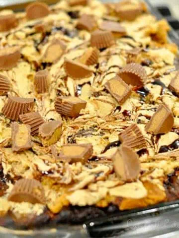 frosting, chocolate, and peanut butter cups on tops of a cake.