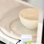 Microwave with a bowl and vinegar for cleaning, labeled as a secret weapon.