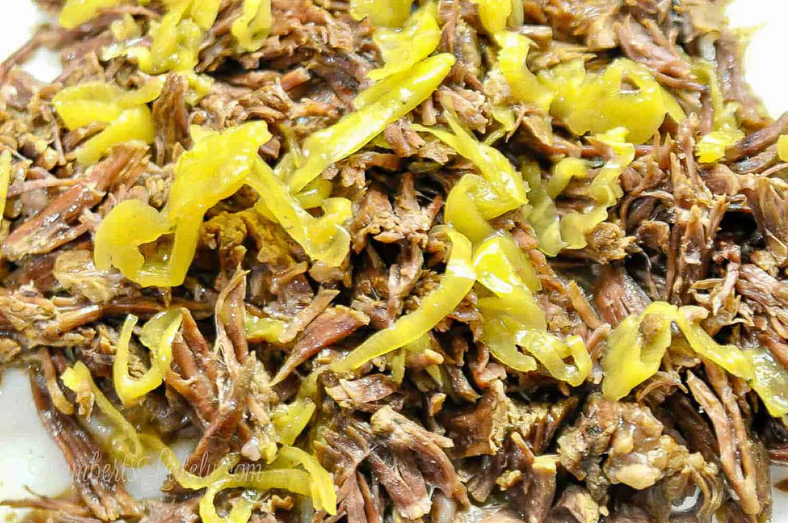 close up of mississippi pot roast covered in sliced pepperoncini peppers.