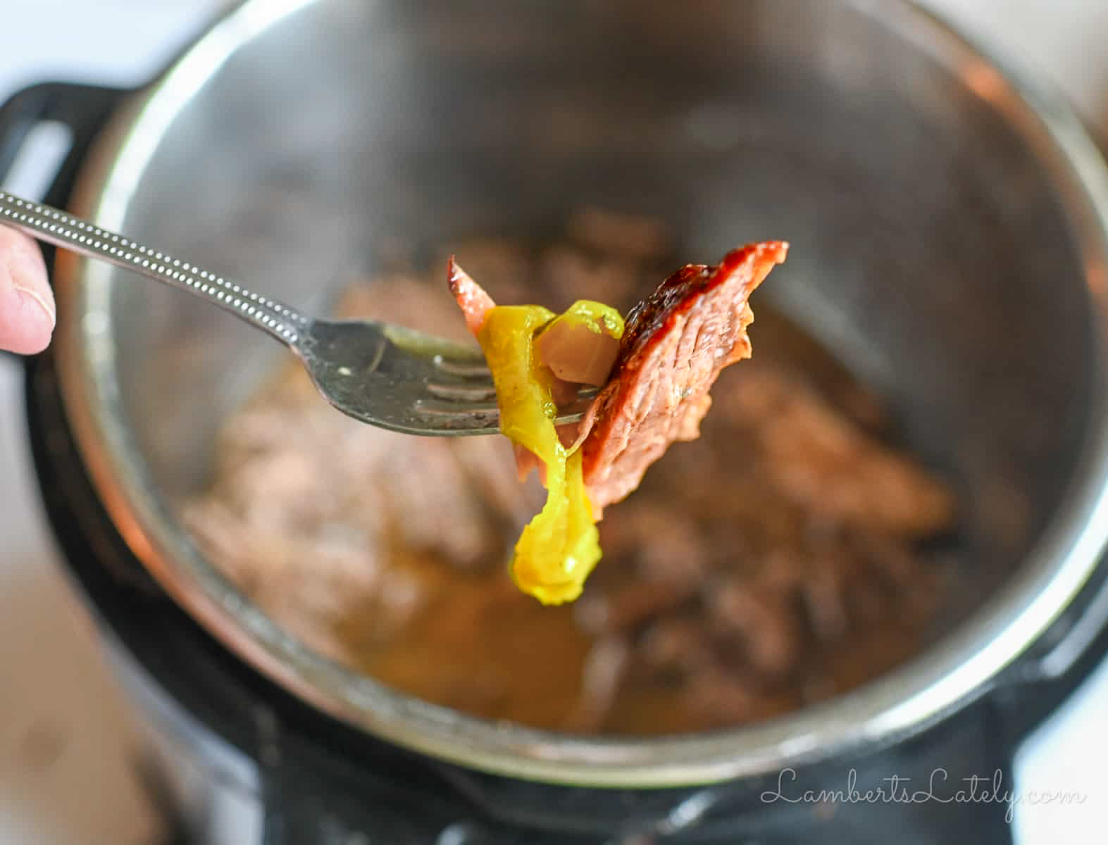 piece of pot roast on a fork with a pepperoncini pepper.