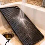 Cast iron griddle being cleaned with water and salt scrub method in kitchen.