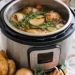 Homemade chicken stock cooking in an Instant Pot with vegetables and herbs.