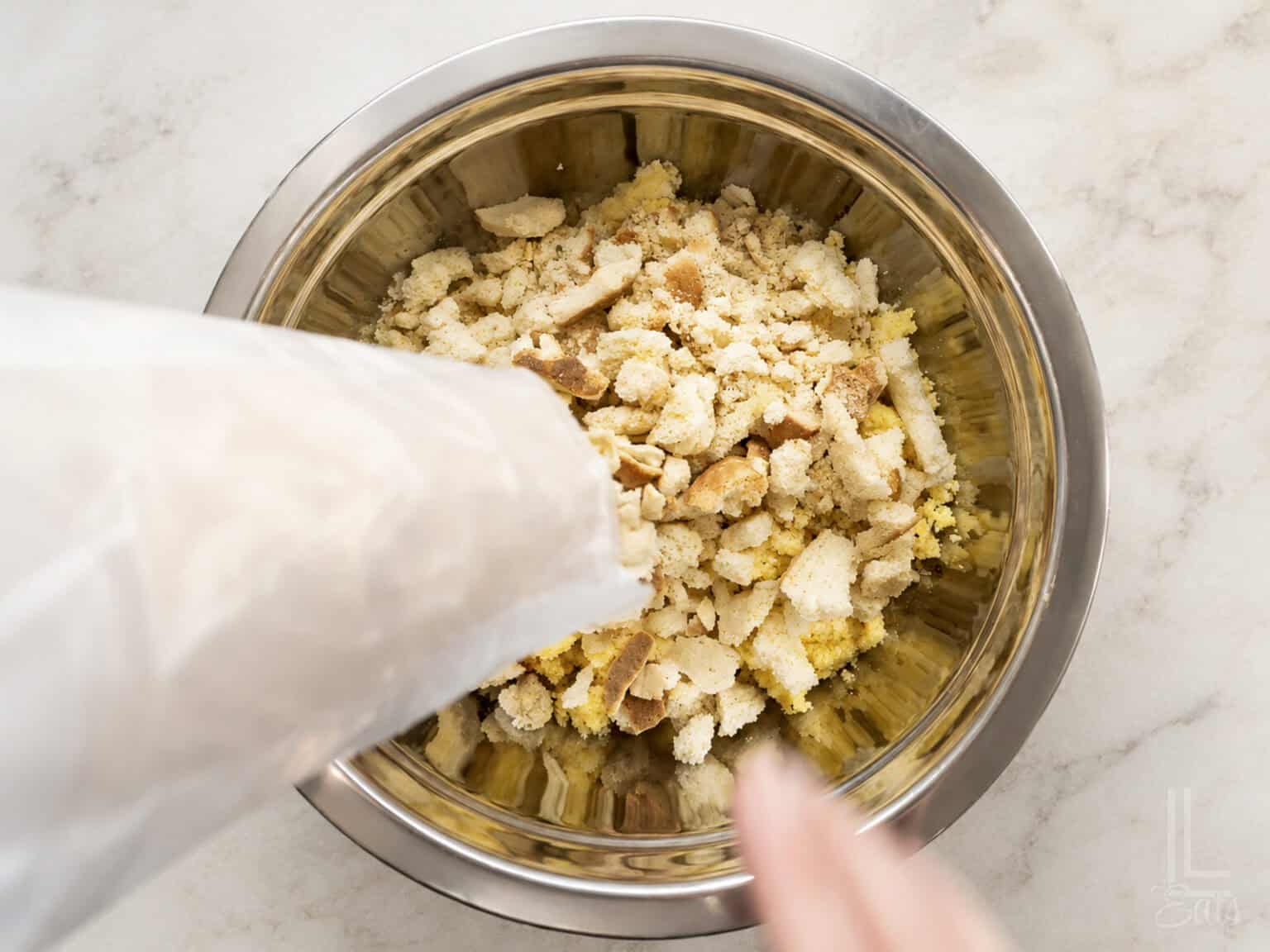 Crumbled cornbread, white bread, and saltines in a metal bowl for dressing.