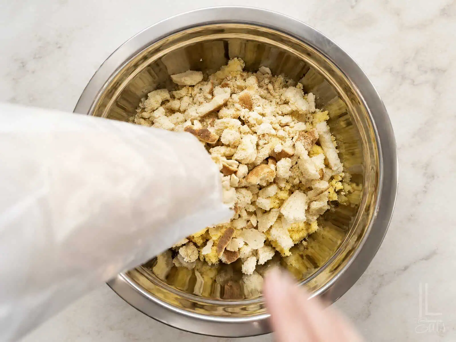 Crumbled cornbread, white bread, and saltines in a metal bowl for dressing.