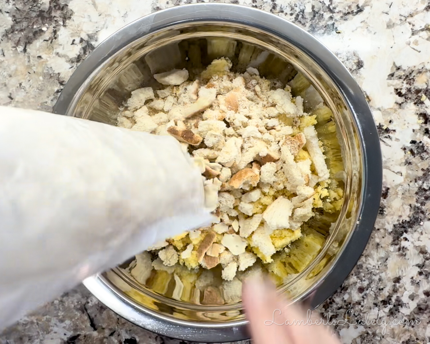 pouring cracker crumbs into a bowl with dried bread and crumbled cornbread.