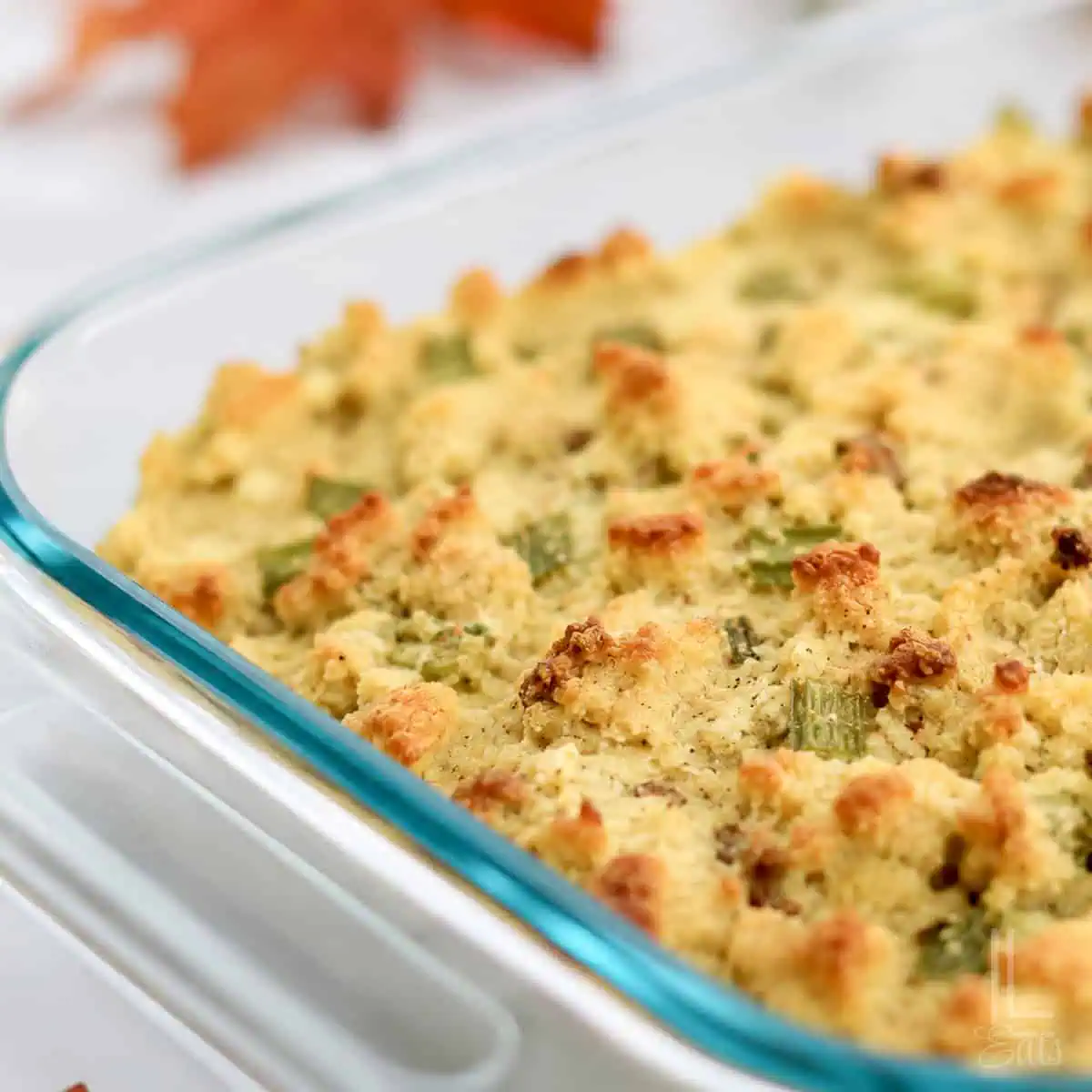 Close-up of homemade Jiffy cornbread dressing with sausage in a glass baking dish.