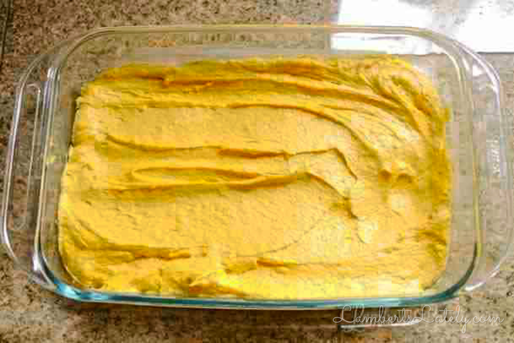 pumpkin spice cake batter spread in a baking dish.